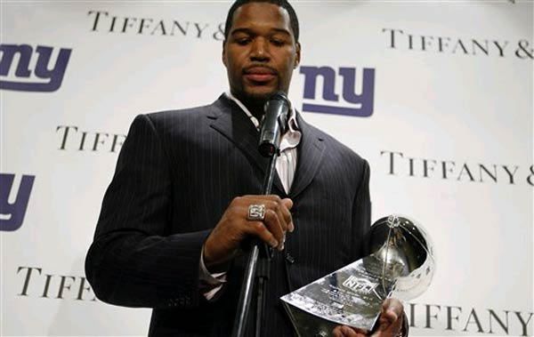 New York Giants defensive end Michael Strahan admires his Super Bowl ring while speaking to the press.